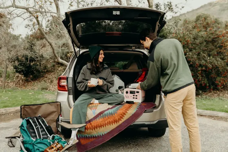 Travelers loading bags into car for road trip adventure.